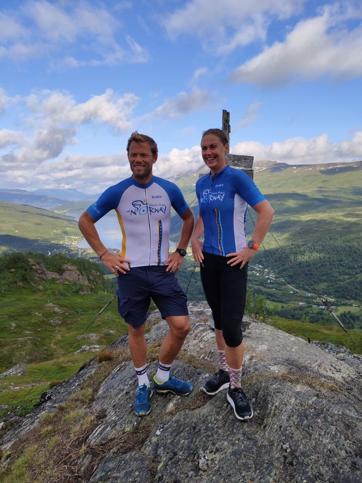 Arctic Race-ambassadørene Gunn-Rita Dahle Flesjå og Thor Hushovd utenfor Snolkehytta med Gratangen i bakgrunnen. I Gratangen starter den fjerde og siste etappen i Arctic Race of Norway 2021.