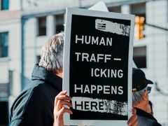 Antall ofre for menneskehandel som ble oppdaget rundt om i verden falt i 2020 med 11 prosent fra året før. Her står en mann med et skilt hvor det står: «Human trafficking happens here», eller «Menneskehandel skjer her» for å sette fokus på menneskehandel som et globalt problem i dag. Foto: Hermes Rivera/Unsplash.