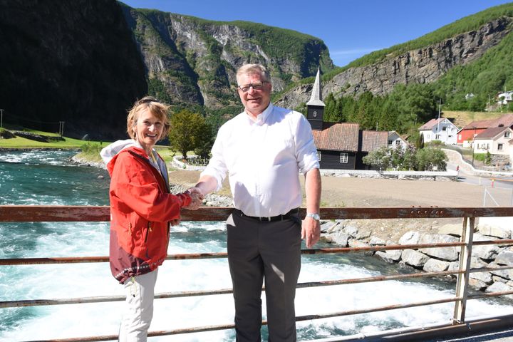 Skred- og vassdragsdirektør i NVE, Anne Britt Leifseth og ordførar i Aurland kommune Noralv Distad, ved Flåmselvi med Flåm kirke i bakgrunnen. Foto: Erik Due