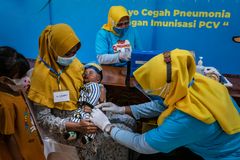 Uul Masula, 28, holder barnet sitt mens han får pneumokokkvaksine i Indonesia. UNICEF