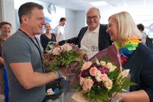 Prosjektansvarlig Oliver Kofler blir overrakt blomster av direktør Eli Grimsby i KID. I bakgrunnen, leder for hovedstyret i Svømmeklubben Speed, Ola Viken. Foto: Ken Opprann.