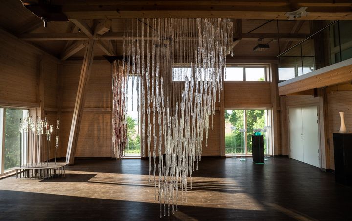 Det største, monumentale verket "Stille, faren er over" fyller midten av det store rommet på Glasslåven, med lange glassformer hengende i piggtråd. Foto: Elin Osjord