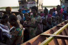 Flyktninger i Sør-Sudan venter på å komme av båten i Mingkamen (Foto Phil Moore/Plan)