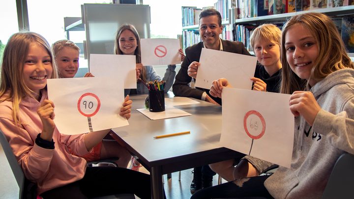 Alle barn kan bli med på tegne- og skrivekonkurransen om transport og trafikk. Her får samferdselsminister Knut Arild Hareide de første bidragene fra elever på Munkerud skole. Fra venstre: Silje, Jakob, Maja, Knut Arild, Eik og Leonora. Foto: SD/Henrik Jonassen.