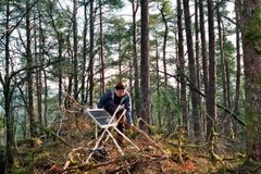Carolyn Rosten monterer lydlogger og solcellepanel i skogen.