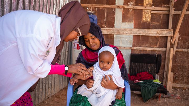 Her får vesle Muniish Cadan vaksine på et lokalt helsesenter i Puntland, Somalia. Det er et såkalt «outreach»-senter som når mødre og barn i utkantstrøk med vaksiner, fødselsinformasjon og annen helsehjelp. ©UNICEF/UN0758717/Ekpu VII Photo