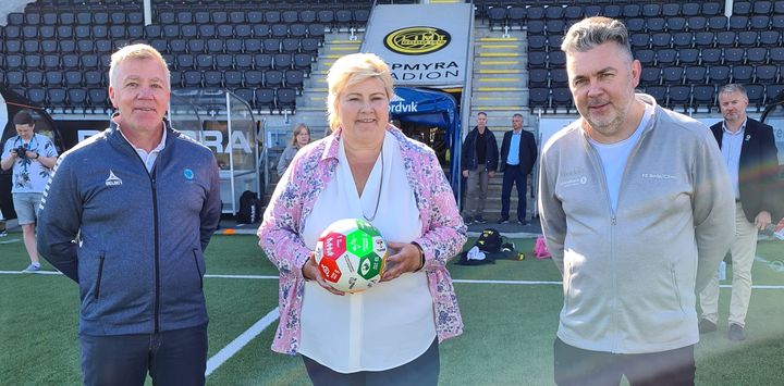 Fotballstiftelsens daglige leder Arne Knoph og Bodø/Glimts daglige leder Frode Thomassen fikk en fantastisk nyhet av statsminister Erna Solberg. Foto: glimt.no