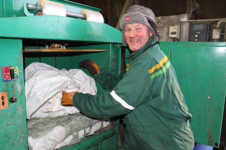 KOMPRIMERER: Bjørnar Schei, som er en av bøndene som har benyttet seg av Felleskjøpets pilotprosjekt innen plast, rister rundballeplasten og legger den rett i komprimatoren slik at den er klar til transport fra gården.   