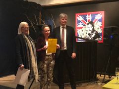 Forretningsgården Fagerhaug er en av de viktigste i Ørjes handelshistorie og ligger midt i sentrum. Stedet er en viktig del av bybildet, og vitner om steds- og sentrumsutviklingen gjennom mange tiår. Eier har i år fått 470.000 kroner til fasader og vinduer. På bildet overrekker t.h. klima- og miljøminister Ola Elvestuen symbolet på årets støtte til eier Hilde Nyborg Braarud. T.v. styreleder i Kulturminnefondet, Helen Bjørnøy. (Foto: Line Lyngstad/Kulturminnefondet)
