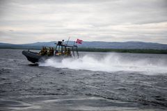 Pasvikelva markerer deler av grensen mellom Norge og Russland. Vernepliktige soldater patruljerer elva med båt. Den russiske byen Nikel i bakgrunn. Foto: Forsvaret