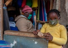 En ung jente bruker munnbind for å beskytte seg sammen med sin mor i en av butikkene i Lilongwe, Malawi. Foto: AFP/NTB