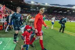 Kaptein Heltne Nilsen tilbyr Jesper en trygg hånd når han entrer gressmatta som maskot foran 14.000 tilskuere på Brann Stadion. Foto: Herman Borgstrøm Tangen