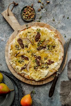 Pizza er en av nordmenns absolutte helgefavoritter. Her har den reist fra Italia til Norge, og er toppet med hvit saus, reinsdyrbiff, sopp, pære, hvitost og blåmuggost. Foto: MatPrat/Sara Johannessen.
