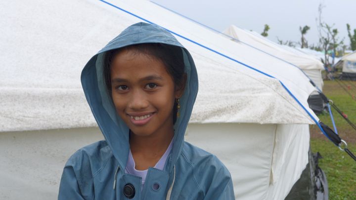 Kemberly (12), søsteren Marjorie og mor Wilifreda fikk huset sitt ødelagt i tyfonen. Nå bor de i en teltleir der de får matvarehjelp og jentene får undervisning av Plan. (Foto: Plan)