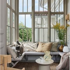 GLASSVERANDA: Her får vakre vinduer være uten gardiner for å slippe mest mulig av naturen inn i rommet, men puter og pledd gir lun varme og forsterker kosen.