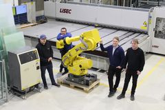 Petter Rakvåg, fabrikksjef Ernest Mielus, Bendik Rakvåg og Roy Rakvåg ved den 4. og foreløpig siste investeringen. Lisec lamnatskjærebord og den gule roboten som skal ta av tilskåret laminert glass og stable på transportstativer.