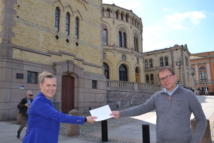 Lene Vågslid tar imot forslaget fra Audun Bringsvor foran Stortinget. Foto: Sigbjørn Larsen