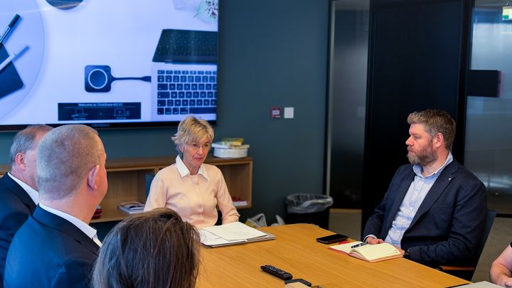 Personer sitter rundt et møtebord under en mekling om Landsoverenskomsten for elektrofagene. En av deltakerne tar notater.