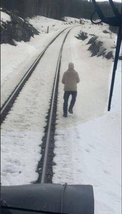 Mann går nesten i skinnegangen rett foran toget