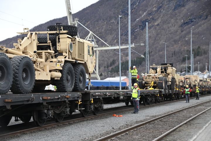 Militære biler og lastebiler på jernbanevogner.