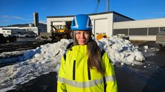 Strekningssjef Laila Remmen i gult vernetøy og hjelm står foran en snødekt bakgrunn ved lokstallen i Mo i Rana.