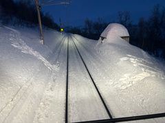 Snødekte togskinner med tydelige skispor på tvers av banen.