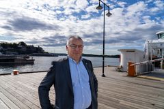 Mann i halvfigur med kai og lettskyet vær i bakgrunnen.