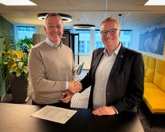 To menn håndhilser i et kontorlandskap.