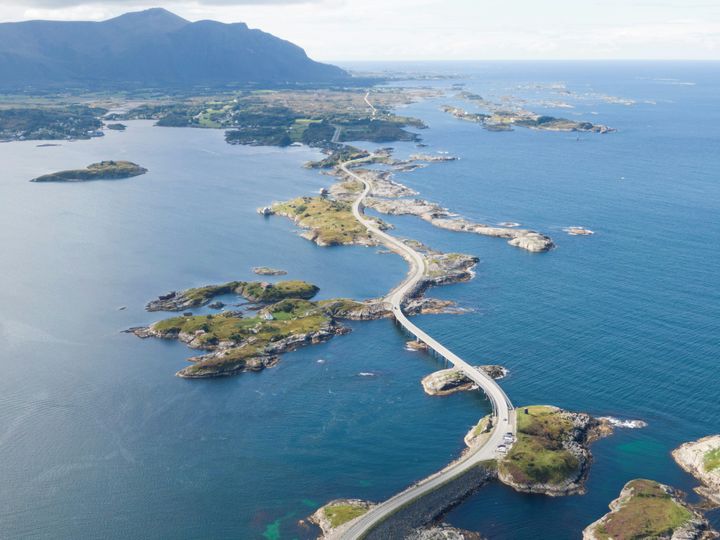 Luftfoto av fylkesvei 64 over Eldhusøya mot Averøya i Møre og Romsdal, omgitt av hav og små øyer.
