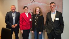 Bilde av fire personer som står foran et kunstverk under et møte i Energidepartementet.