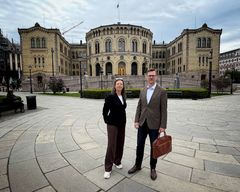 Mann og kvinne i helfigur med Stortinget i bakgrunnen.