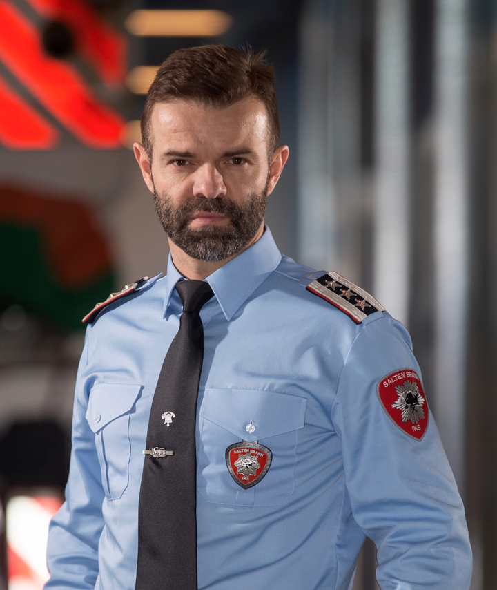 Mann i halvfigur i brannuniform, ser mot kamera.