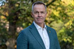 Portrett av Øivind Brevik, administrerende direktør i Samfunnsbedriftene, iført blå dressjakke og hvit skjorte, fotografert utendørs med høstfarget løv i bakgrunnen.