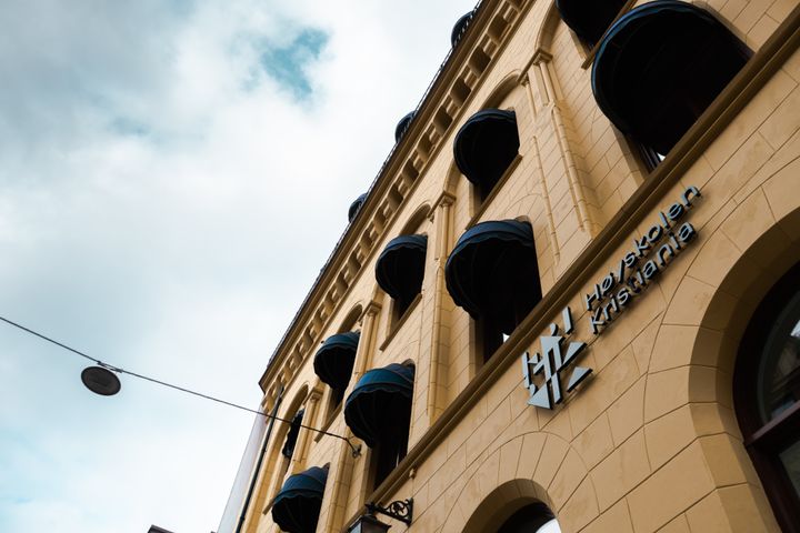 Bygning med høye buede vinduer og skilt som sier "Høyskolen Kristiania".