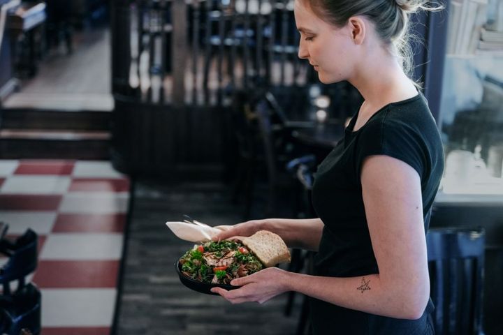 Bildet viser en kvinnelig servitør som holder en tallerken med mat.