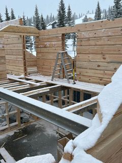 Fotografi av en et hytte som bygges, og gardintrapp på noen løse planker. Betonggulv under