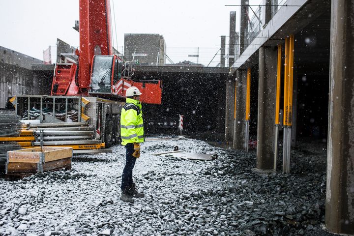 Mann med hjelm og vest ser utover en byggeplass.