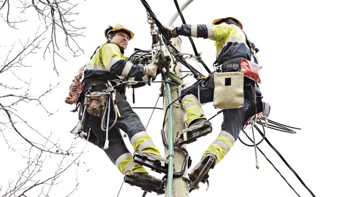 Bildet viser to personer i en høyspentmast.