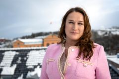 Dame med brunt skulderlangt hår, rosa tweed-jakke ser inn i kamera