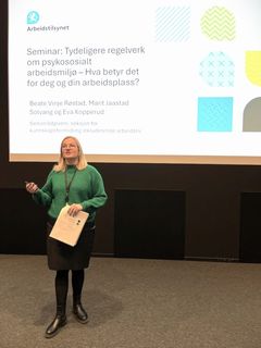 Bildet viser Eva Irene Kopperud på en scene med en skjerm bak seg.