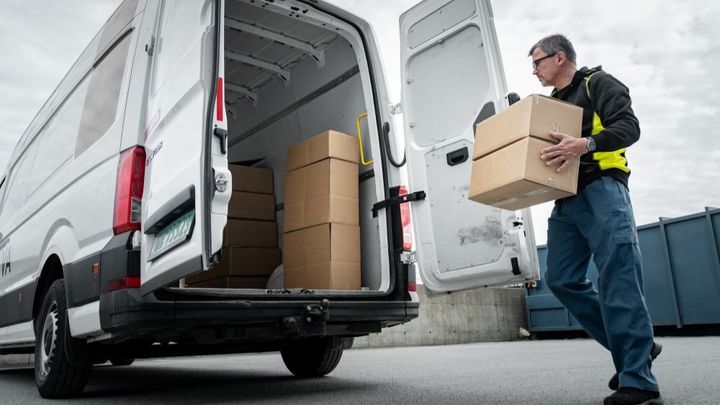 Bildet viser en mann som bærer en pakke inn i en varebil.