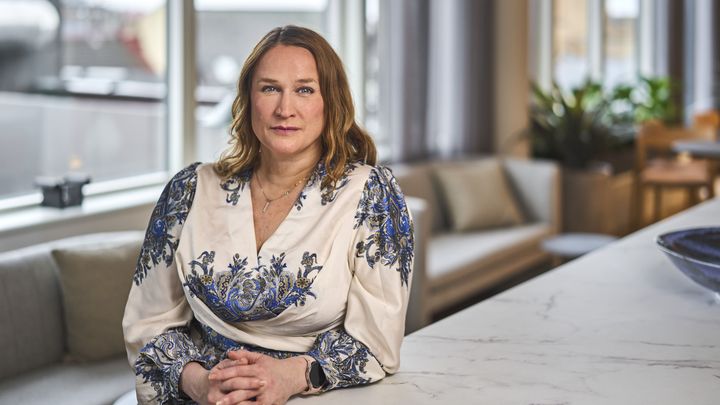 Kvinne med skulderlangt og mørkeblondt hår ser inn i kamera.