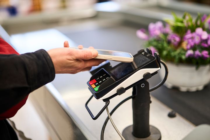 Bildet viser en person som betaler med mobil hos en butikk.