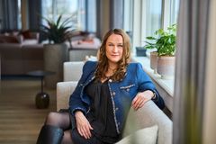 Kvinne med brunt halvlangt hår sitter ved en benk og ser alvorlig ut