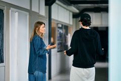 Kvinne står på et kjøkken og snakker med en ungdom som står med ryggen til