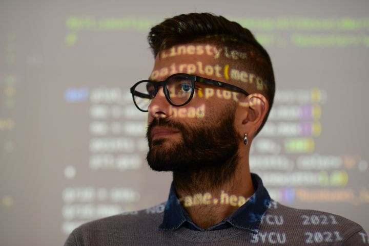 Foreleser Fabrizio Palumbo står foran en skjerm som viser Python-koding.
