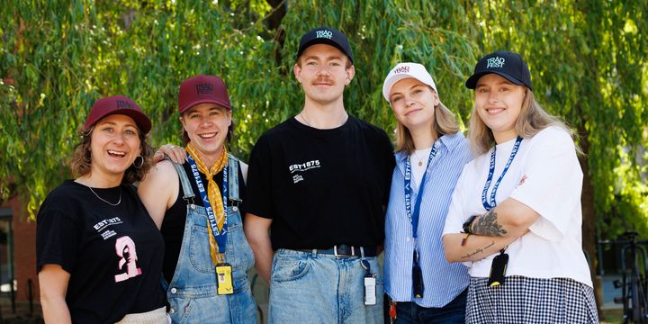 Fem studenter står ute foran et tre. De har på seg Trådfest-capser.