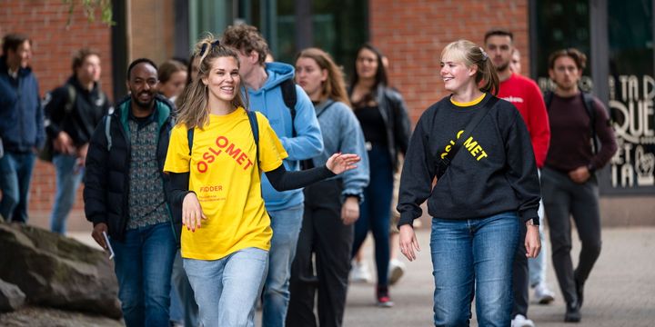 En gruppe studenter går på OsloMets campus i Pilestredet. En har gul OsloMet-tskjorte.