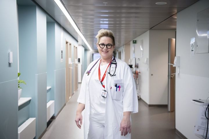 Kvinnelig lege i hvit frakk står i en sykehusgang