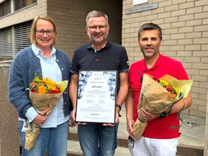 Tre personer som holder diplom og blomster